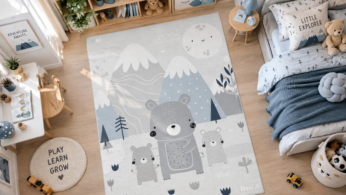 A beautiful kids rug in a nursery room. Rug has mountains and bear family. And bed, table and toys in the room. 