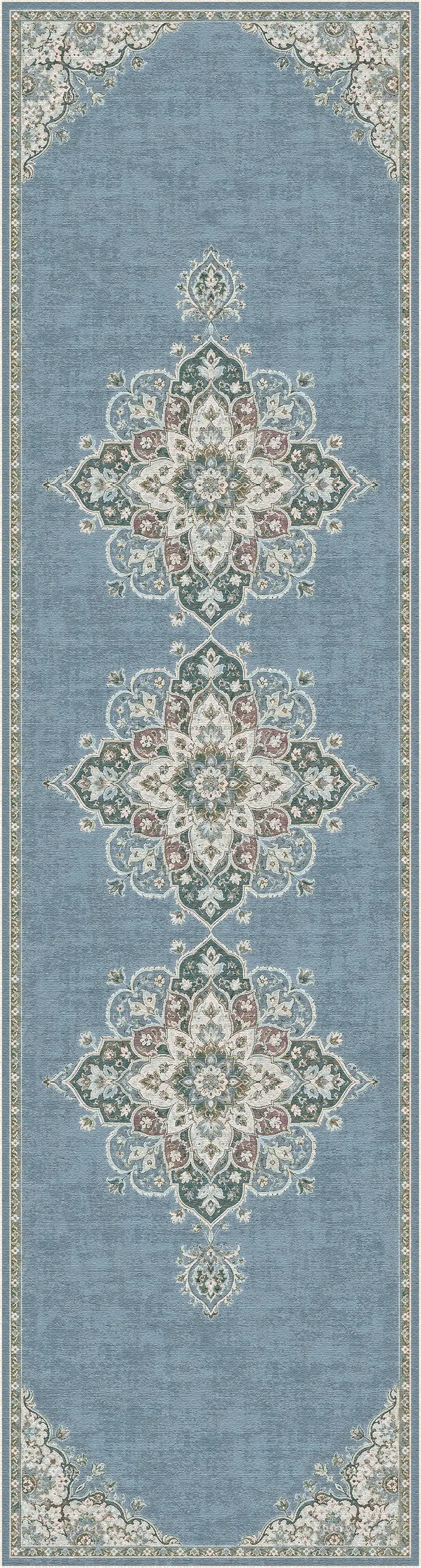 A rectangular area rug with a dusty blue background and ornate central medallions in cream, beige, and muted pink, bordered by matching decorative corner and edge motifs.
