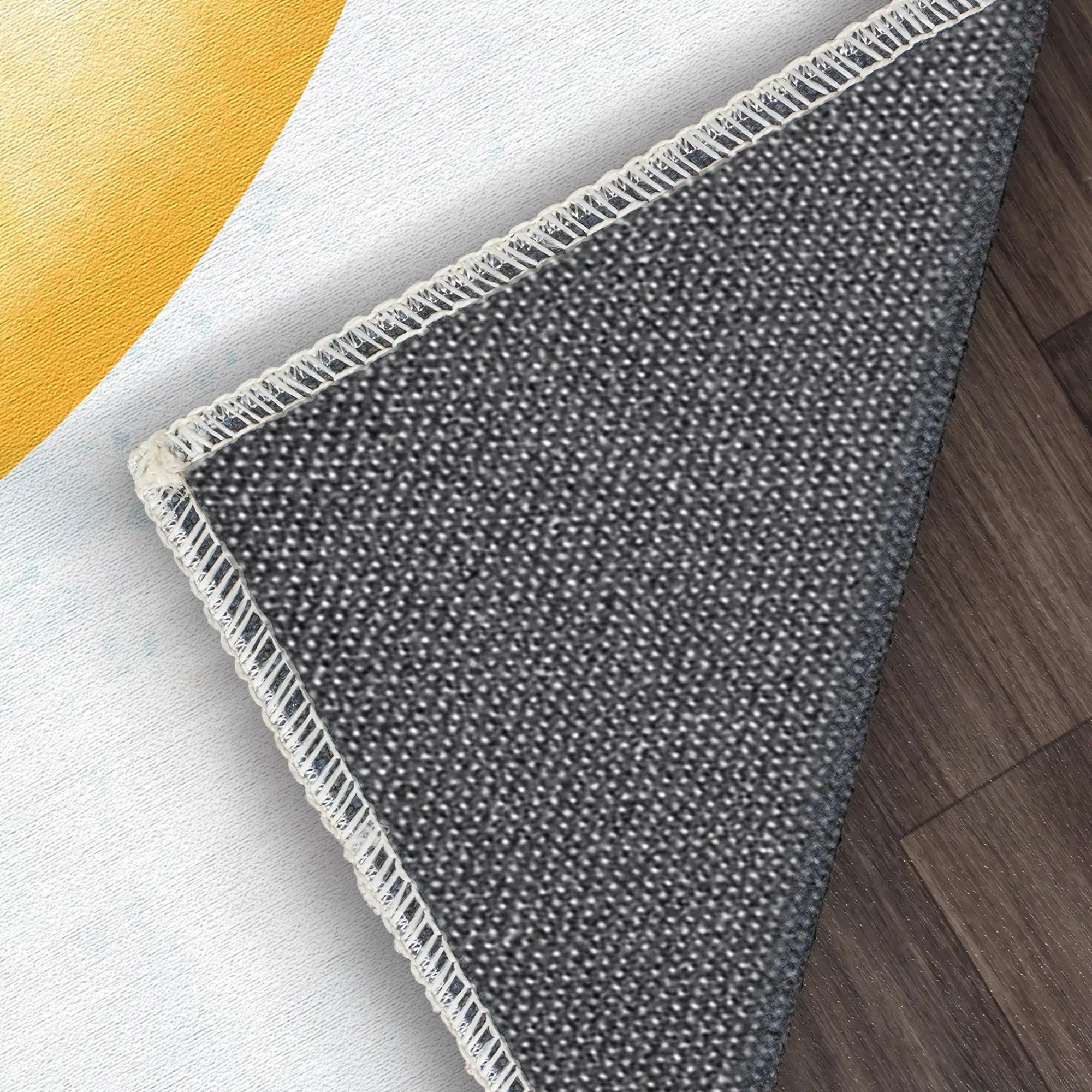 Gray textured rug on a wooden floor with a yellow circular object in the corner.