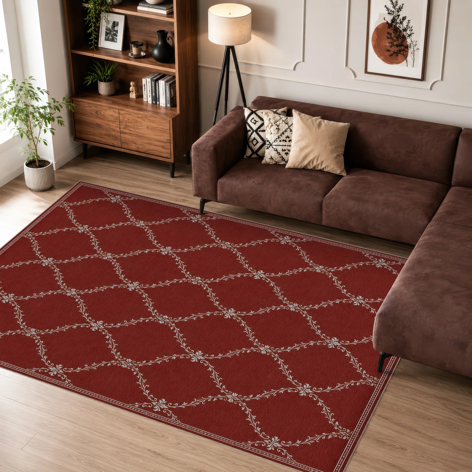 A red rectangular lattice area rug with a beige trellis pattern, shown in a styled living room setting next to a brown sectional sofa and wooden bookshelf.