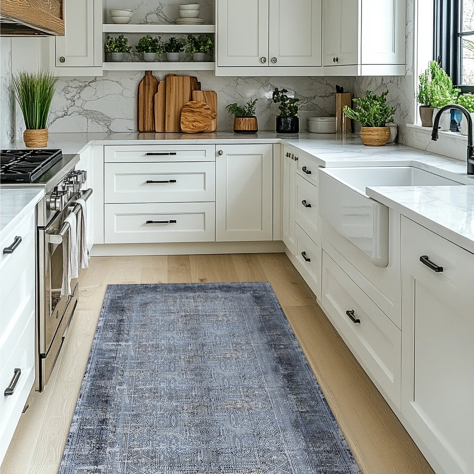 Modern kitchen with white cabinets, marble countertop, and blue patterned rug on wooden floor.